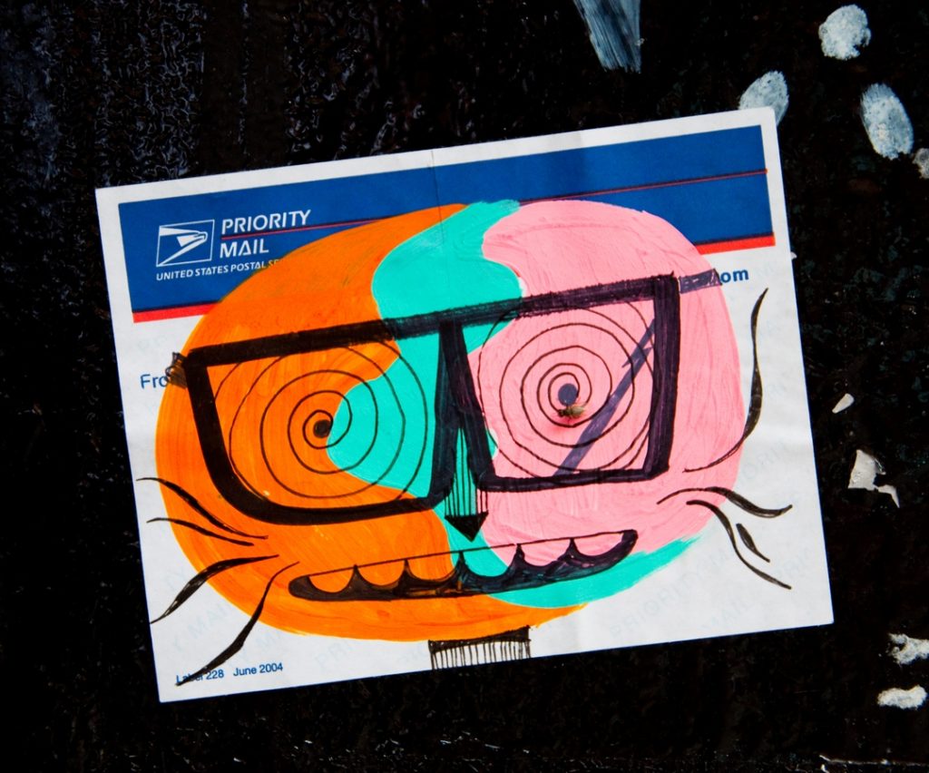 US Popstal sticker with colourful cartoonm face by street artist Mjar