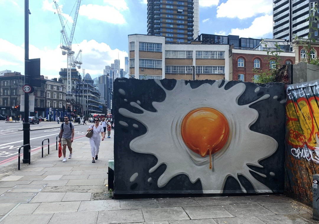 Photorealistic fried egg painted on a building site hoarding in Shoreditch by street artist Woskerski