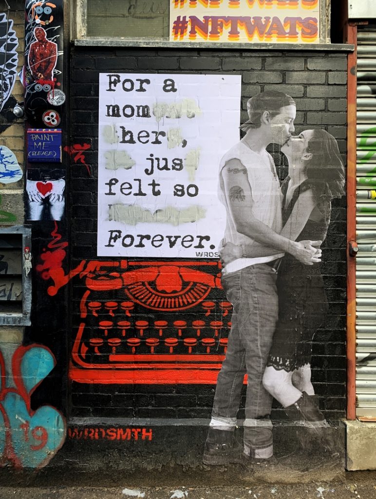 Modified subverted paste-up street art by Wrdsmth, augmented by artist unknown