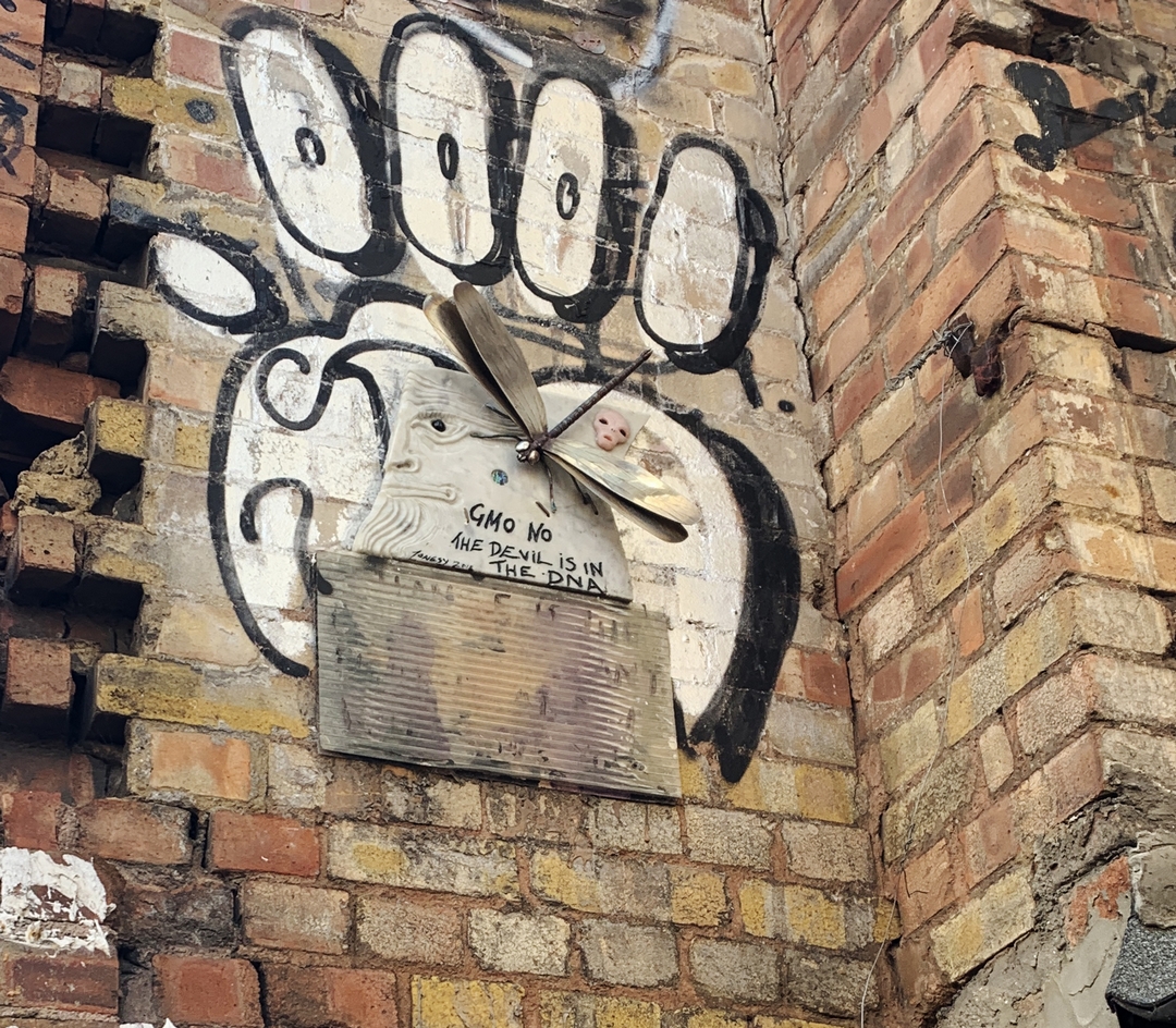 street art in Shoreditch consisting of a metal dragonfly mounted on a sculkpted piece of marble with a face reflecting concerns about genetically modified crops GMO by street artist Jonesy