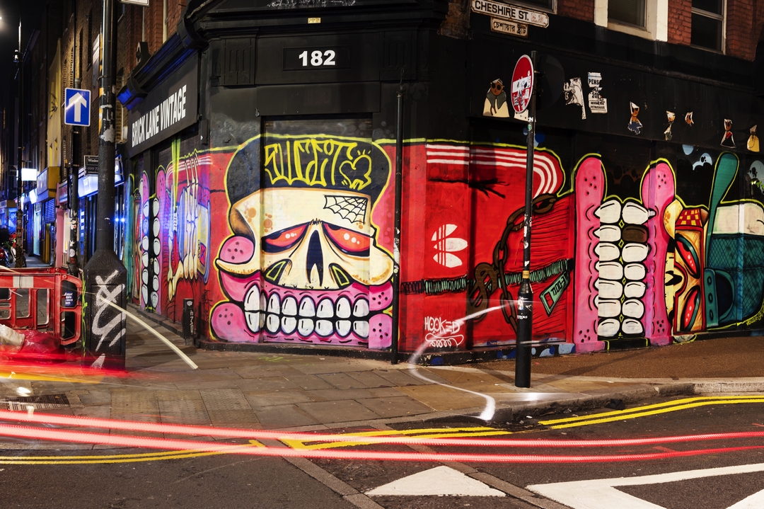 Brake lights in front of colourful graffiti art on a shop shutter on Brick Lane