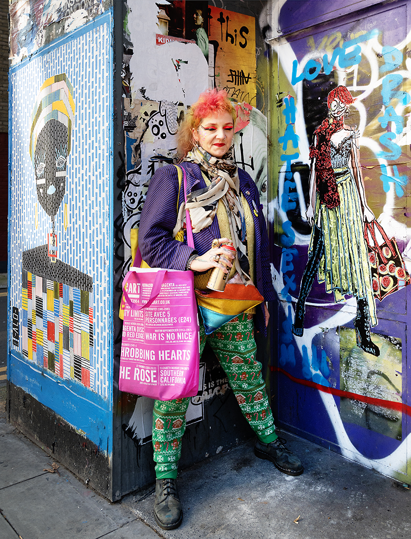 very colourful artist Drash La Krasser in a doorway with her newest artwork and a spraycan in her hand